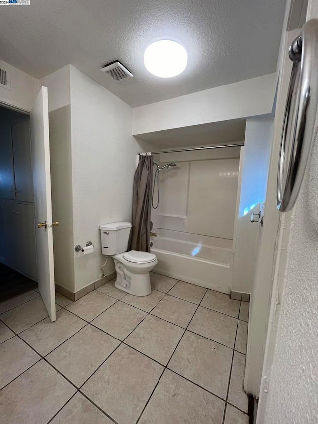 bathroom with shower / bath combination with curtain, a textured ceiling, tile patterned flooring, and toilet