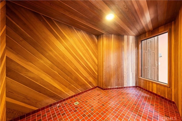 empty room featuring elevator, wood ceiling, and wooden walls