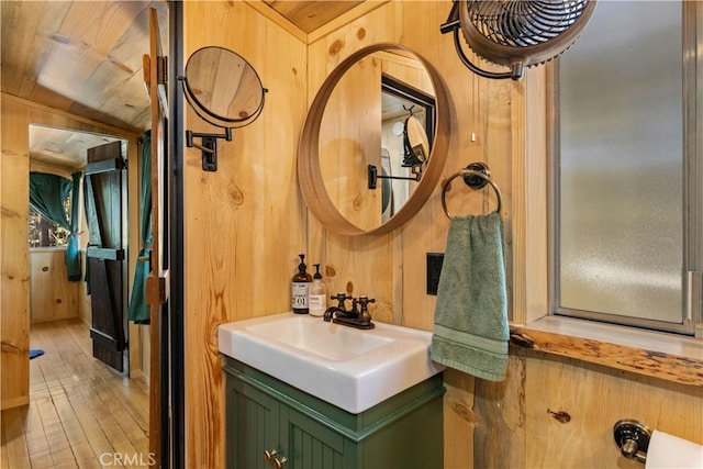 bathroom with hardwood / wood-style flooring, vanity, and wooden walls