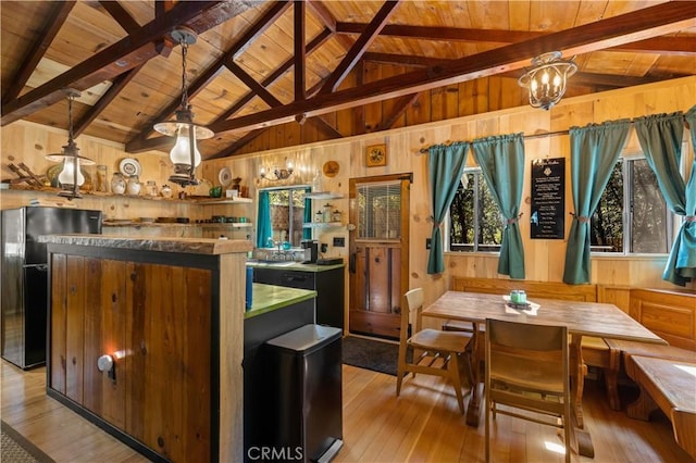 bar featuring hanging light fixtures, black fridge, wooden ceiling, and wood walls