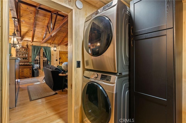 clothes washing area featuring stacked washing maching and dryer, wood walls, wood ceiling, and light hardwood / wood-style flooring