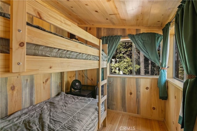 bedroom with hardwood / wood-style flooring, wooden walls, and wooden ceiling