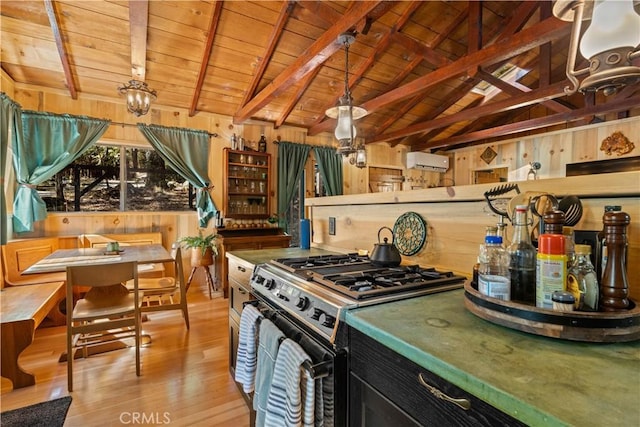 kitchen with gas range, wooden ceiling, wooden walls, and pendant lighting