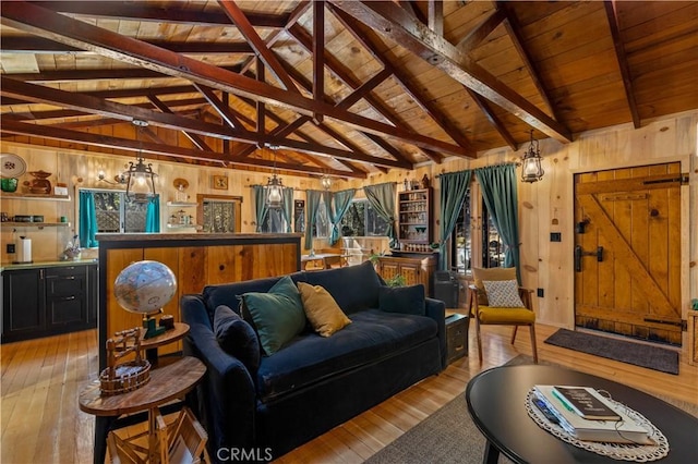 living room with vaulted ceiling with beams, wooden walls, and light wood-type flooring