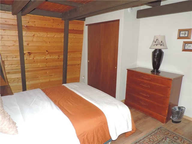 bedroom with beam ceiling, hardwood / wood-style flooring, and wooden ceiling