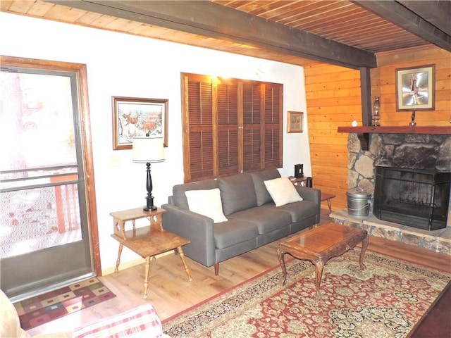 living room with a stone fireplace, wooden walls, beamed ceiling, wood-type flooring, and wood ceiling