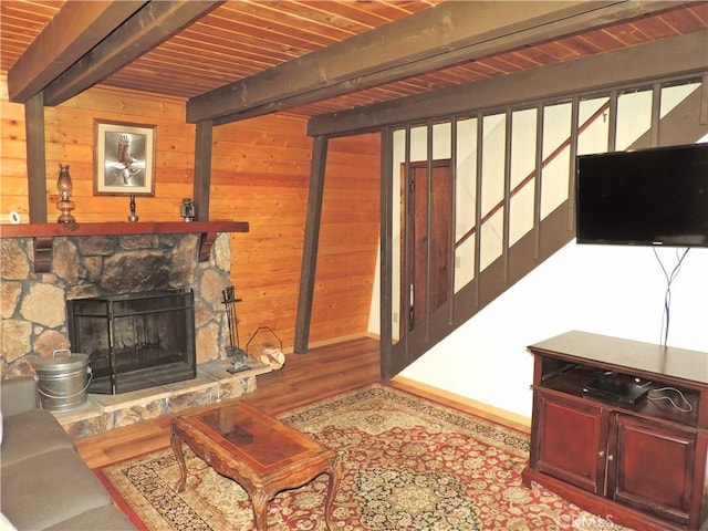 living room with hardwood / wood-style floors, beam ceiling, a fireplace, and wooden walls