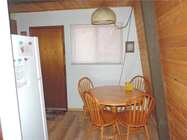 dining room with hardwood / wood-style floors and wooden walls