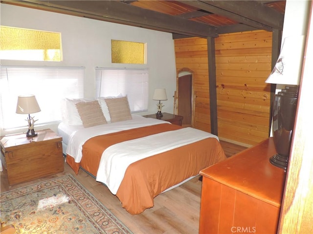 bedroom featuring light hardwood / wood-style flooring and wooden walls