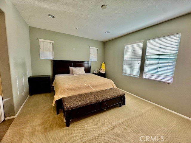 bedroom featuring a textured ceiling and light colored carpet