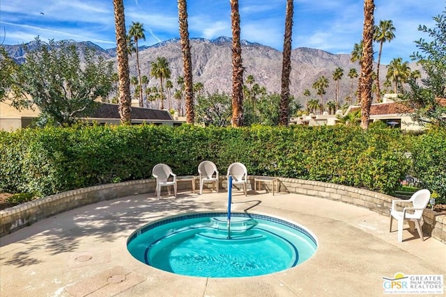 view of pool featuring a mountain view, a patio area, and a hot tub