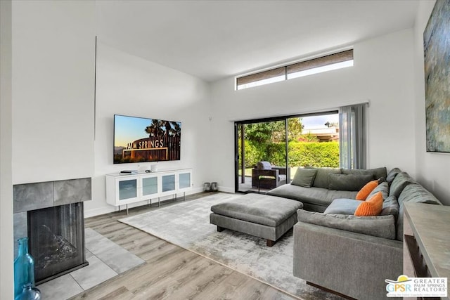 living room with a fireplace, light hardwood / wood-style flooring, and a high ceiling