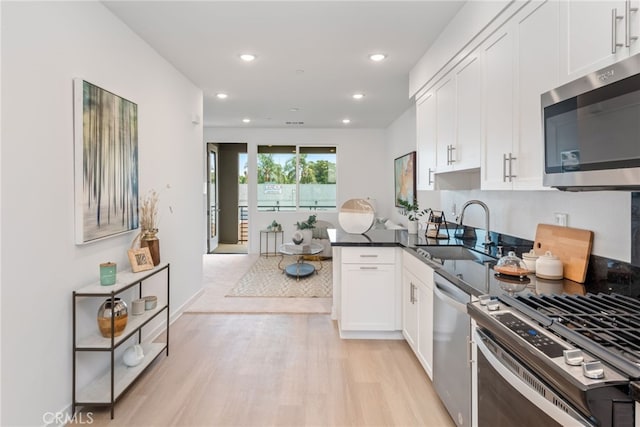 kitchen featuring sink, white cabinets, light hardwood / wood-style flooring, and appliances with stainless steel finishes