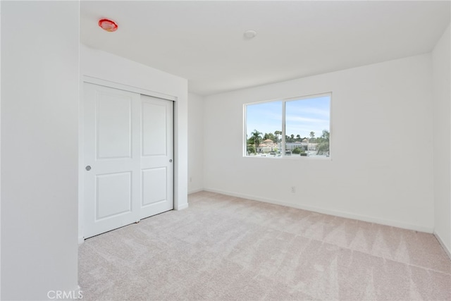 unfurnished bedroom with light carpet and a closet