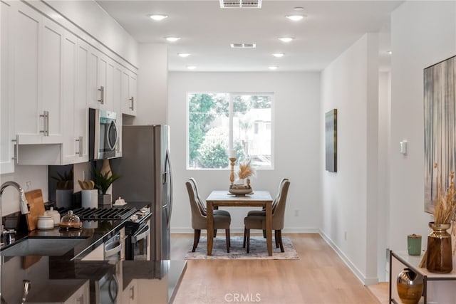 kitchen with white cabinetry, light hardwood / wood-style flooring, stainless steel appliances, and sink