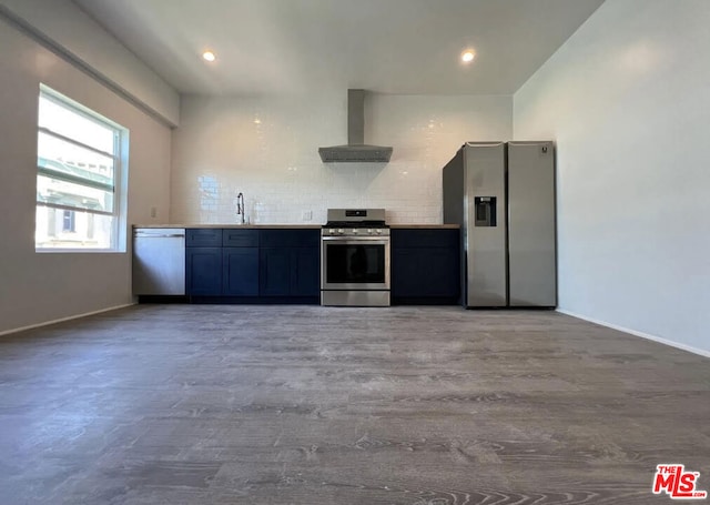 kitchen featuring appliances with stainless steel finishes, backsplash, wall chimney exhaust hood, light wood-type flooring, and sink