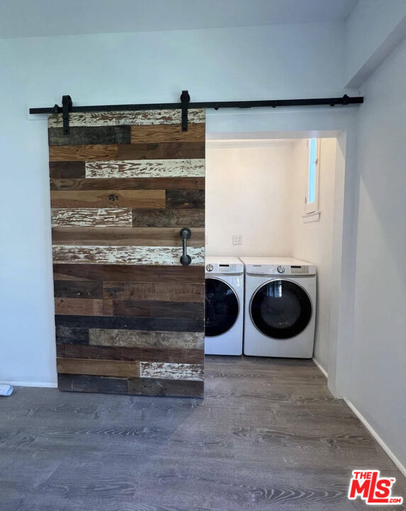 washroom with a barn door, dark wood-type flooring, and washing machine and dryer