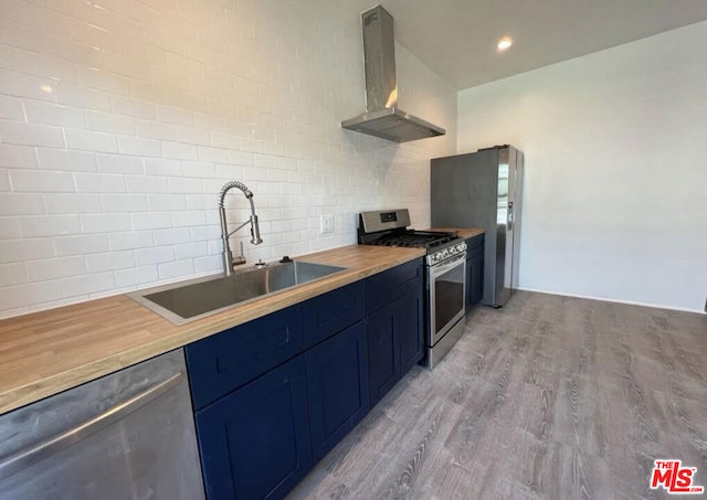 kitchen featuring sink, wooden counters, wall chimney exhaust hood, stainless steel appliances, and light hardwood / wood-style floors