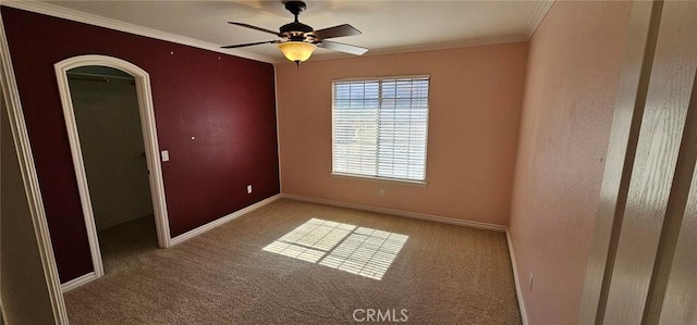 carpeted empty room with ceiling fan, baseboards, and ornamental molding