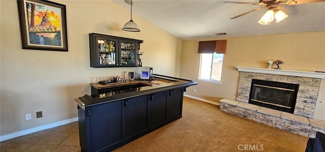 interior space featuring dark cabinetry, visible vents, baseboards, a fireplace, and vaulted ceiling