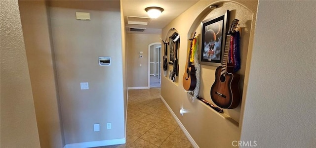 corridor featuring light tile patterned floors, baseboards, and visible vents