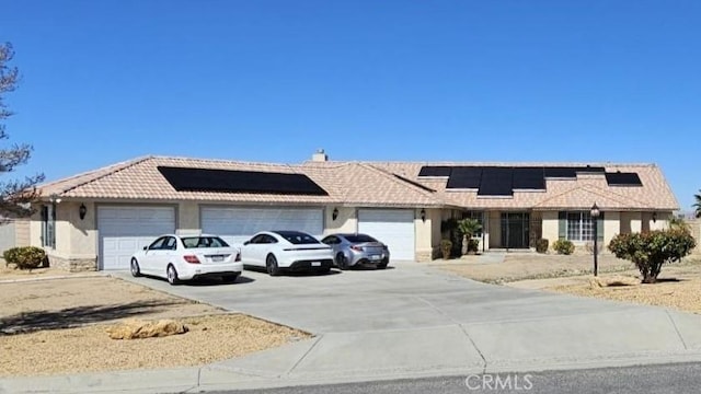 single story home with solar panels, a tile roof, stucco siding, a garage, and driveway