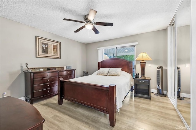 bedroom featuring ceiling fan, light hardwood / wood-style floors, and a textured ceiling