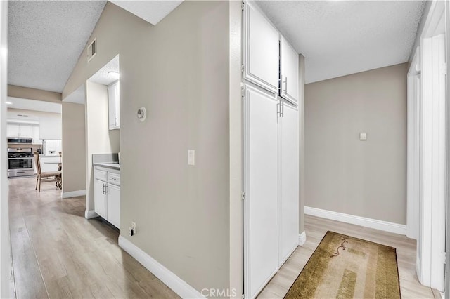 1186 Bottle Tree Way, Hemet, CA 92545 - hallway featuring a textured ceiling and light wood-style flooring