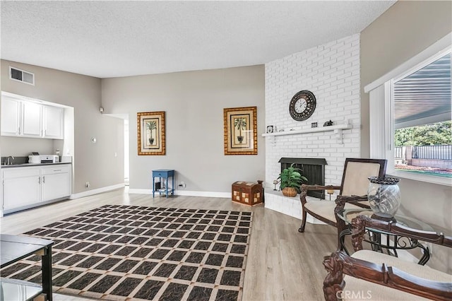 1186 Bottle Tree Way, Hemet, CA 92545 - living room with light wood-type flooring, a brick fireplace, and a textured ceiling