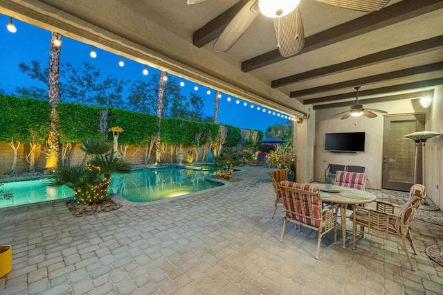 pool at dusk with ceiling fan and a patio