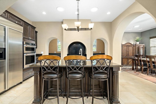 kitchen with a breakfast bar area, dark brown cabinetry, a kitchen island, and appliances with stainless steel finishes