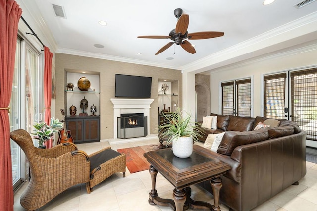 living room featuring built in shelves, light tile patterned floors, ceiling fan, and ornamental molding