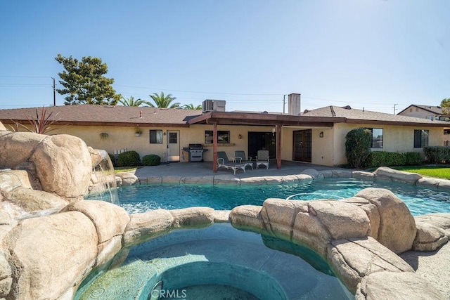 view of swimming pool with an in ground hot tub, pool water feature, a patio, a grill, and cooling unit