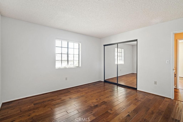 unfurnished bedroom featuring a closet, a textured ceiling, and dark hardwood / wood-style flooring