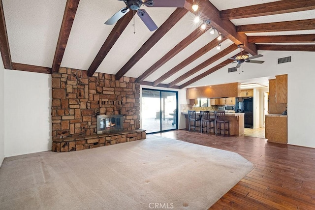 unfurnished living room with ceiling fan, hardwood / wood-style flooring, a fireplace, high vaulted ceiling, and beamed ceiling