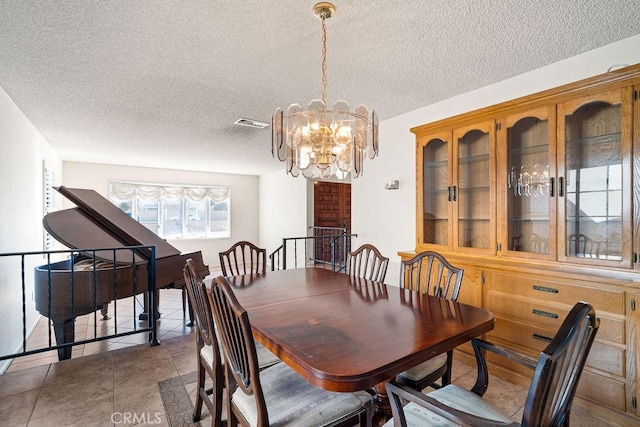 dining room featuring dark tile patterned flooring, a textured ceiling, and an inviting chandelier