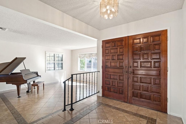 entrance foyer with a textured ceiling, a notable chandelier, and tile patterned flooring