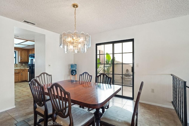 tiled dining area with an inviting chandelier and a textured ceiling