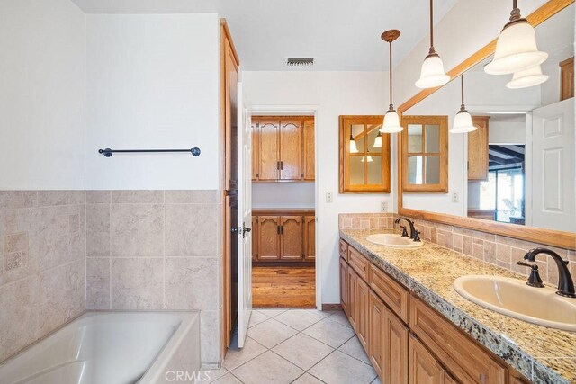 bathroom with a washtub, tile patterned floors, and vanity