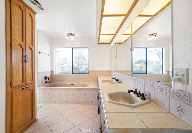 bathroom featuring vanity, a relaxing tiled tub, and tile patterned flooring