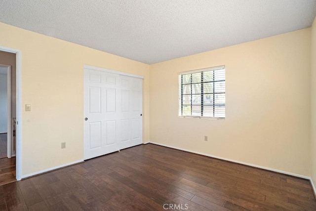 unfurnished bedroom featuring a closet, a textured ceiling, and dark hardwood / wood-style floors