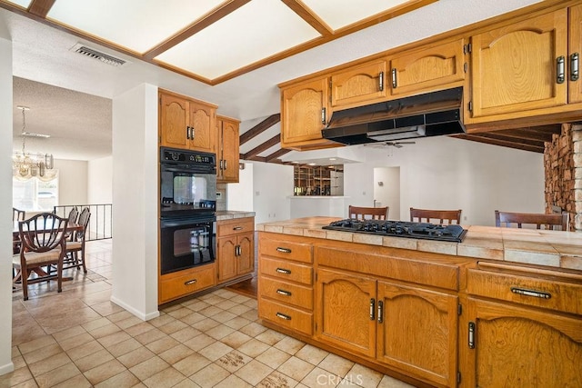 kitchen with black appliances, ceiling fan with notable chandelier, and tile counters