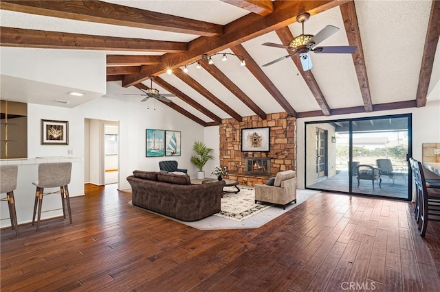 living room featuring dark wood-type flooring, beamed ceiling, high vaulted ceiling, and a stone fireplace