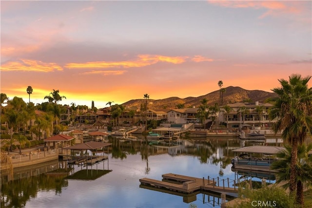 property view of water with a mountain view and a dock