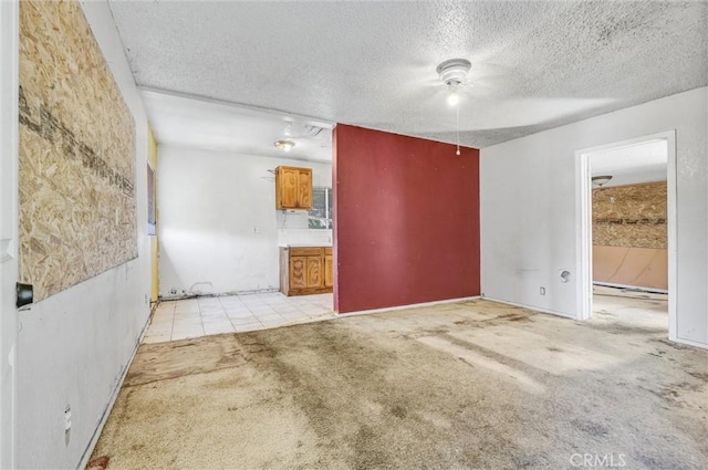 empty room with a textured ceiling, light colored carpet, and a baseboard heating unit