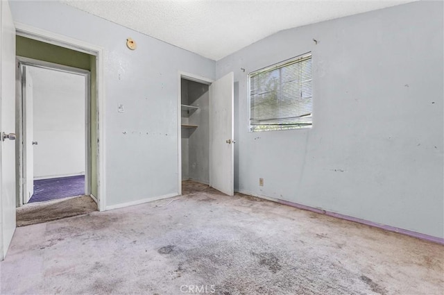 unfurnished bedroom featuring a textured ceiling, a closet, light carpet, and vaulted ceiling