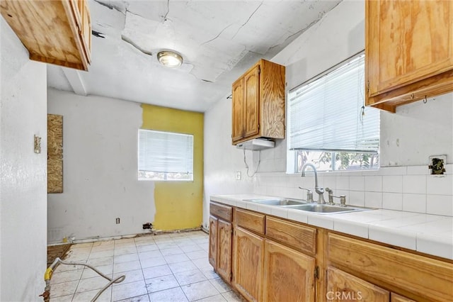 kitchen with backsplash, tile counters, light tile patterned flooring, and sink