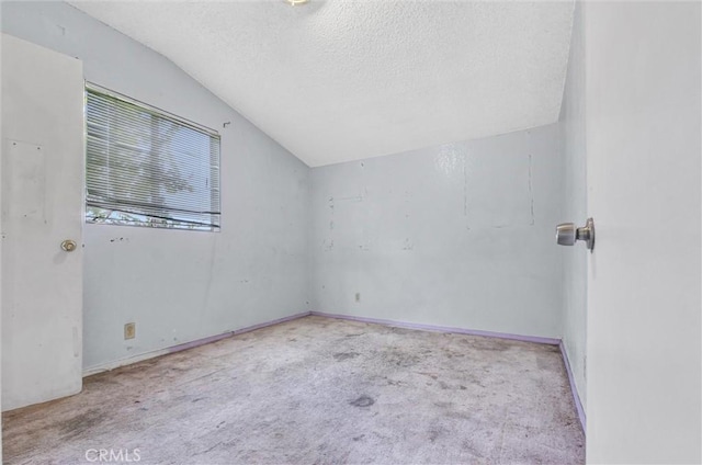 empty room with a textured ceiling, light carpet, and vaulted ceiling