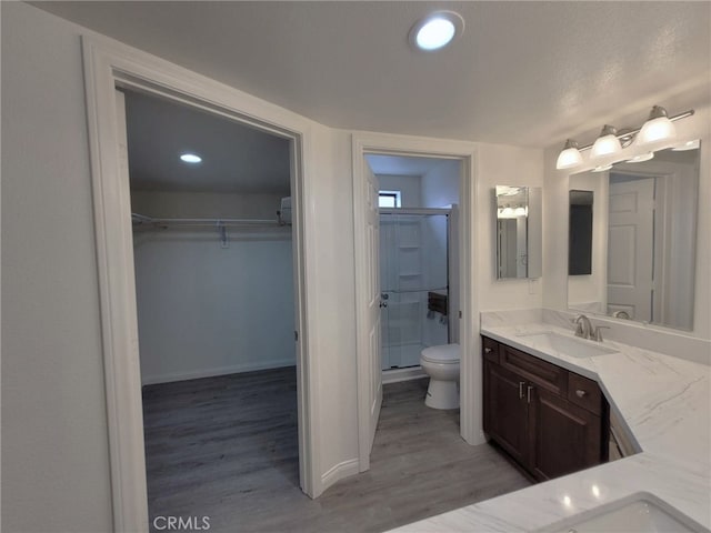 bathroom featuring an enclosed shower, vanity, toilet, and wood-type flooring