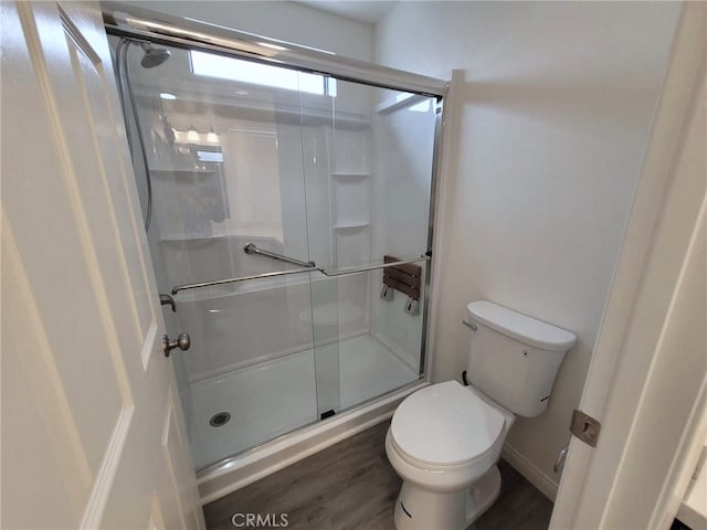 bathroom with walk in shower, toilet, and wood-type flooring